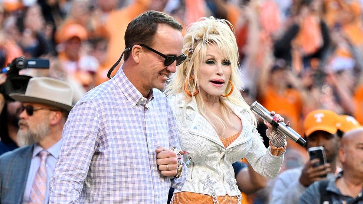 Dolly Parton is escorted by Peyton Manning at Neyland Stadium.