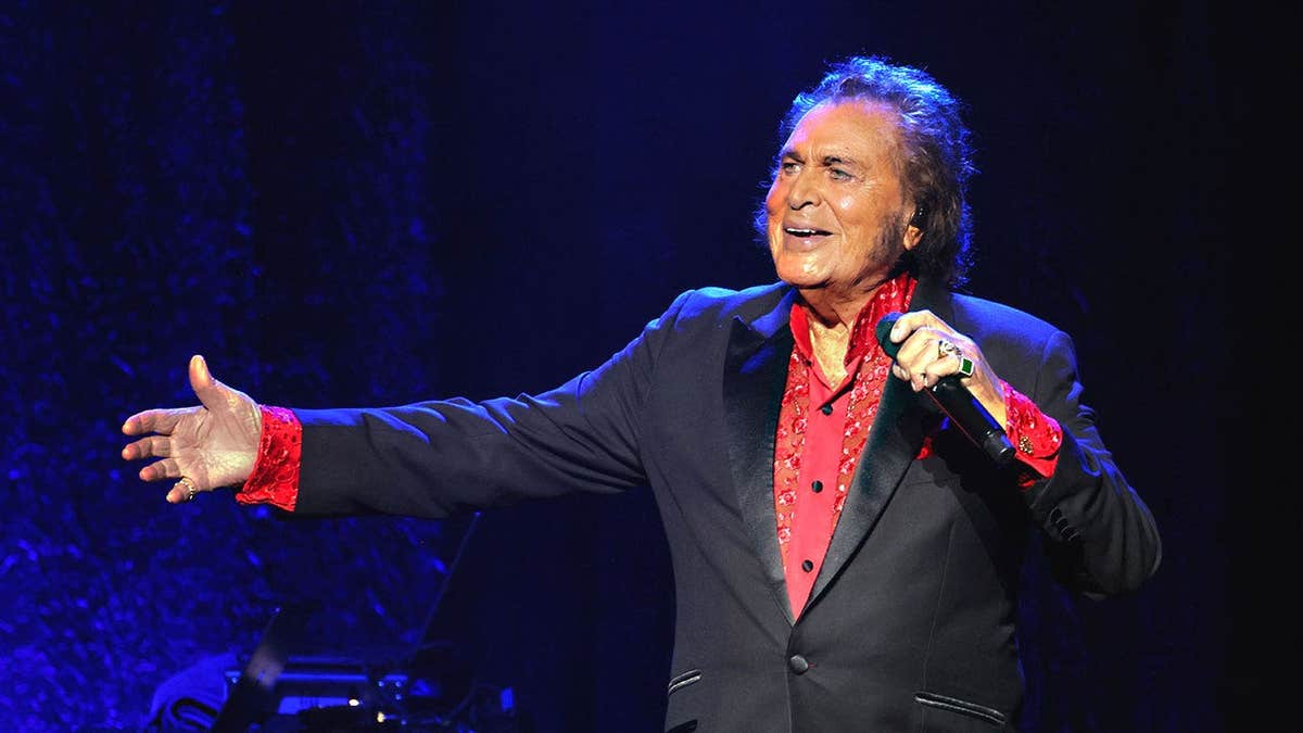 Engelbert Humperdinck performing on stage with his arms stretched out.