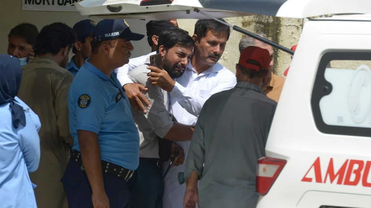 A father, center, of a victim in a fire is comforted as his child's coffin is carried outside a hospital in Islamabad, Pakistan, Wednesday, Aug. 26, 2026.