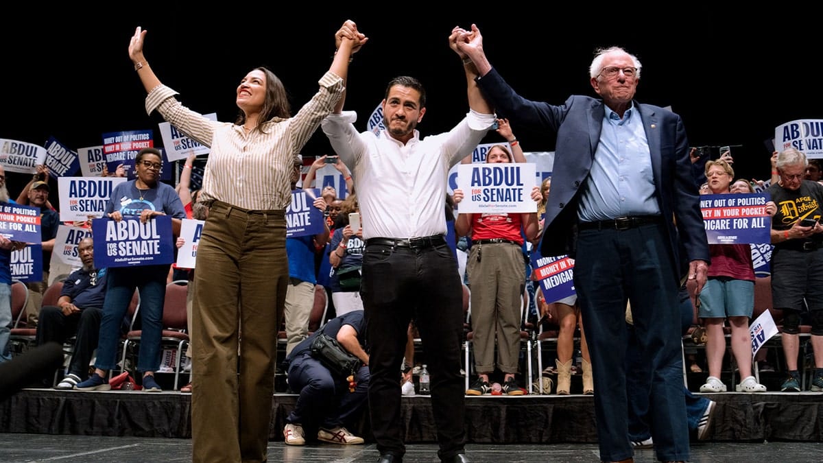 AOC, Abdul El-Sayed, and Bernie Sanders holds hands up during rally