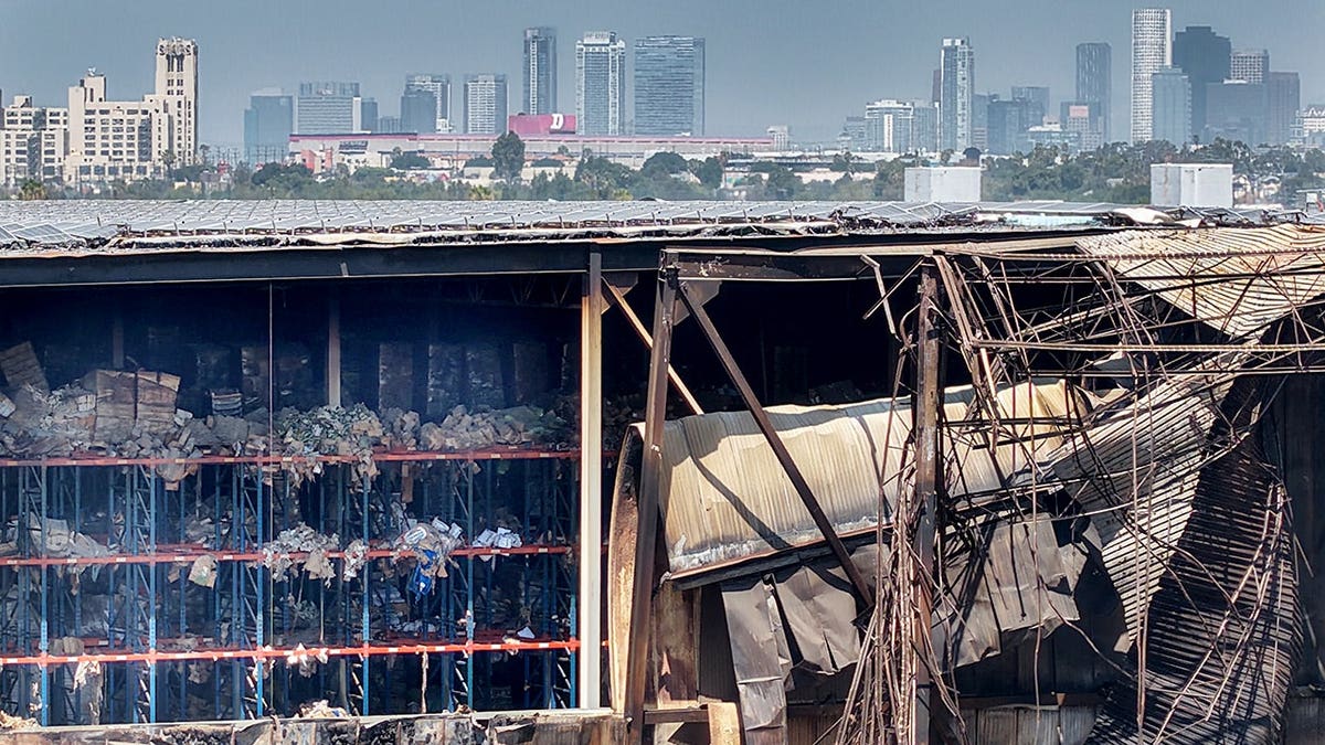 Aerial view of cleanup at Lineage Logistics Cold Storage facility in Boyle Heights with downtown Los Angeles skyline.