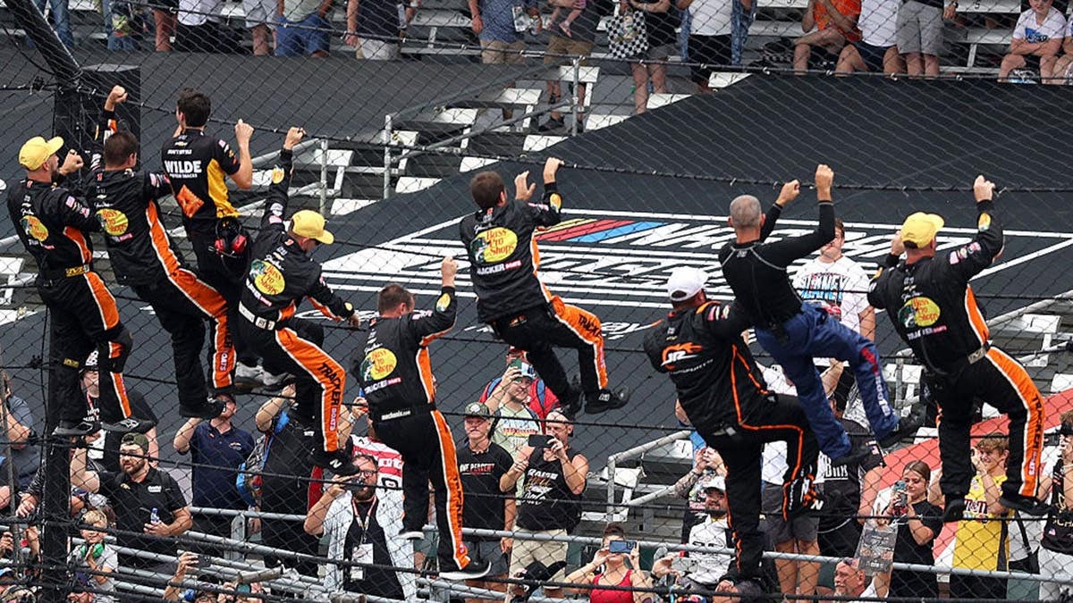Carson Kvapil's crew climbs the fence to celebrate at Indianapolis Motor Speedway.