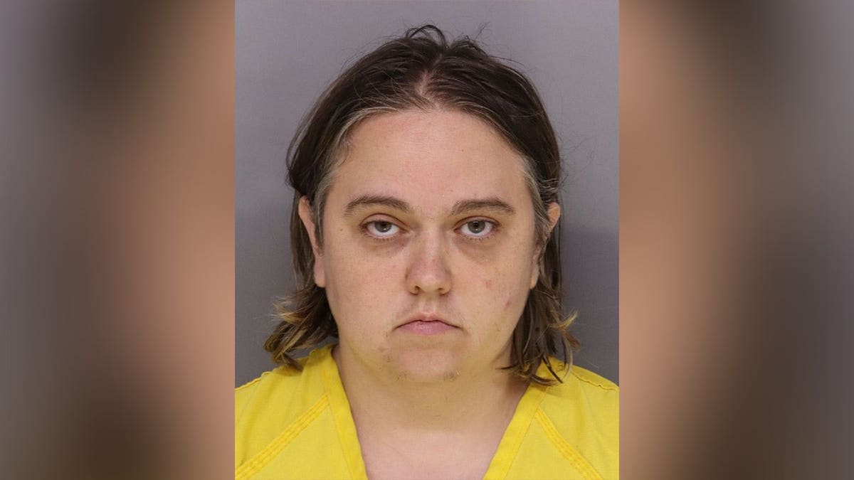 Booking photo of Kaitlin Evans wearing a yellow jail uniform against a gray background.