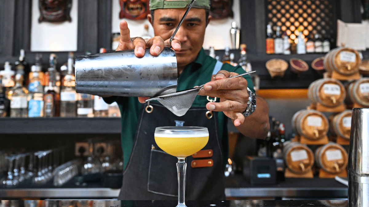 A bartender prepares a drink for a customer.