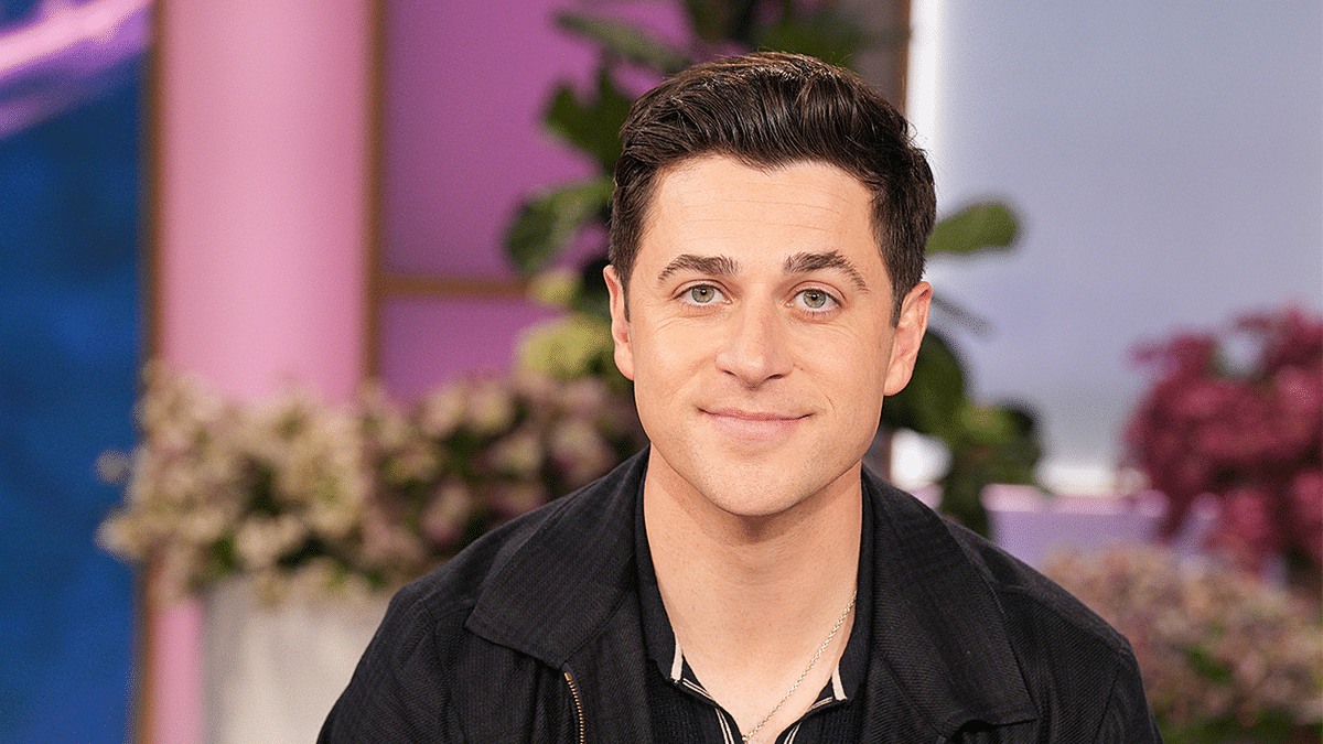 Actor David Henrie sitting with purple background