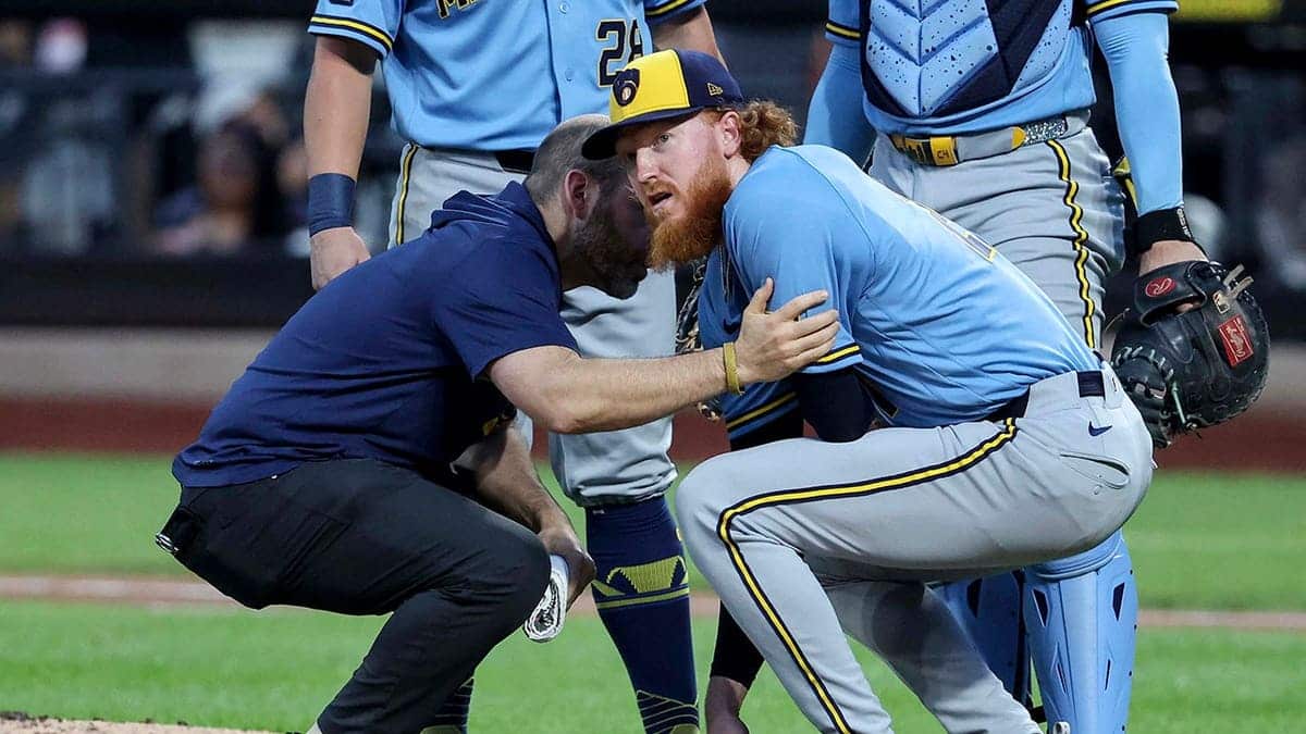 Dustin May crouches after being hit by a line drive during a Brewers-Mets game.