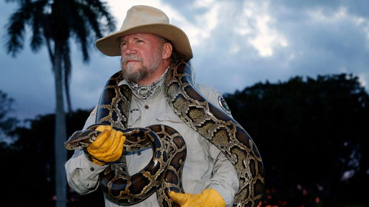 TOPSHOT - Tom Rahill, founder of Swamp Apes, handles a Burmese python as he speaks about the snake at Everglades Holiday Park in Fort Lauderdale, Florida on April 25, 2019.