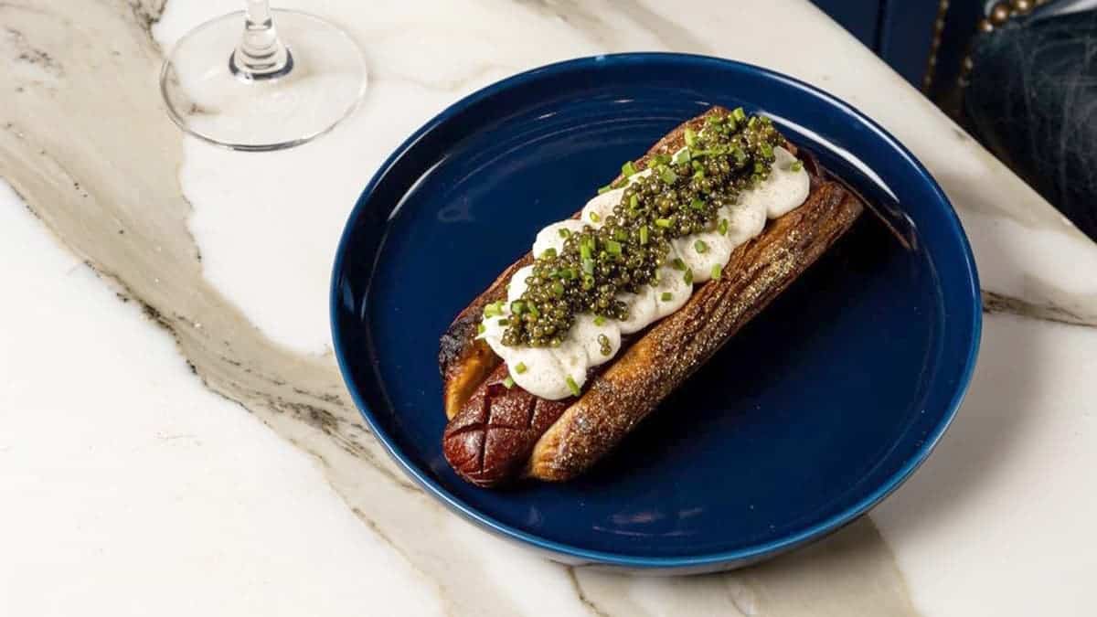 The Golden Glizzy hot dog sits on a plate.