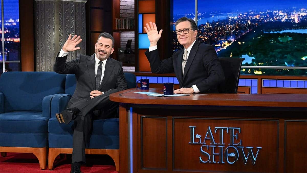 Stephen Colbert and Jimmy Kimmel seated on The Late Show set