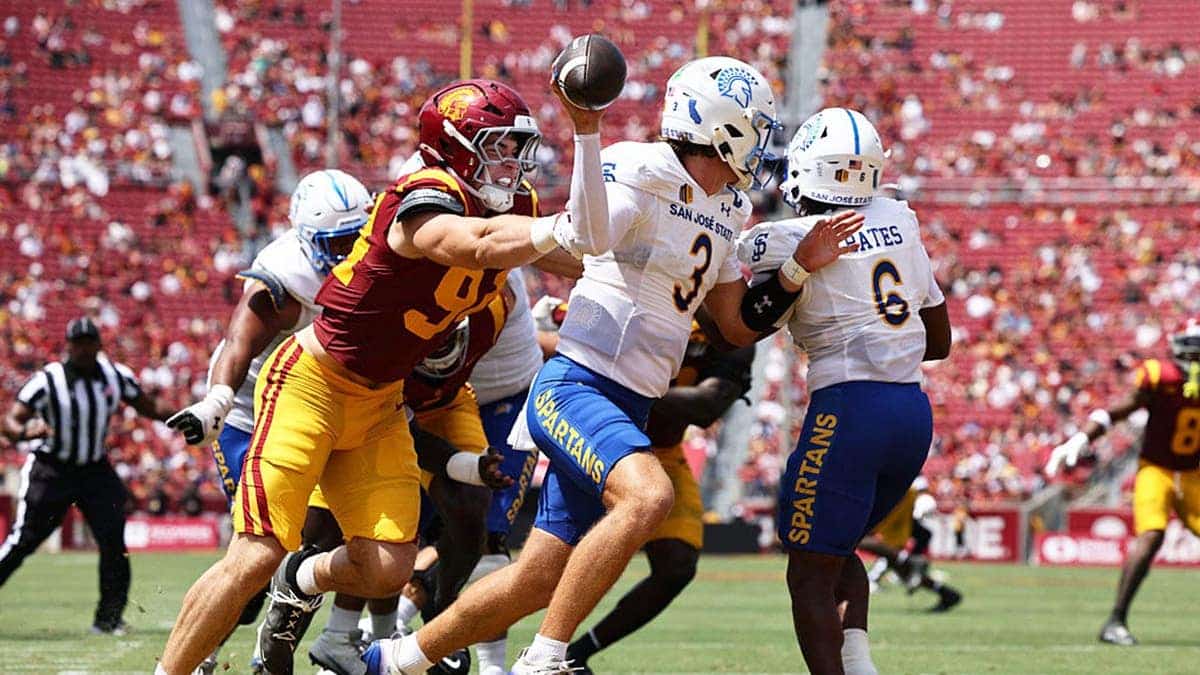 Luke Weaver #3 scrambles while Luke Wafle #94 closes in during a football game.
