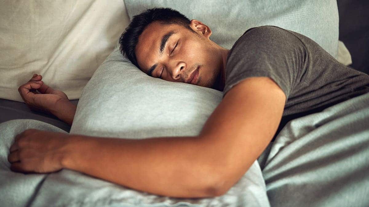 A sleeping person lies on a bed.