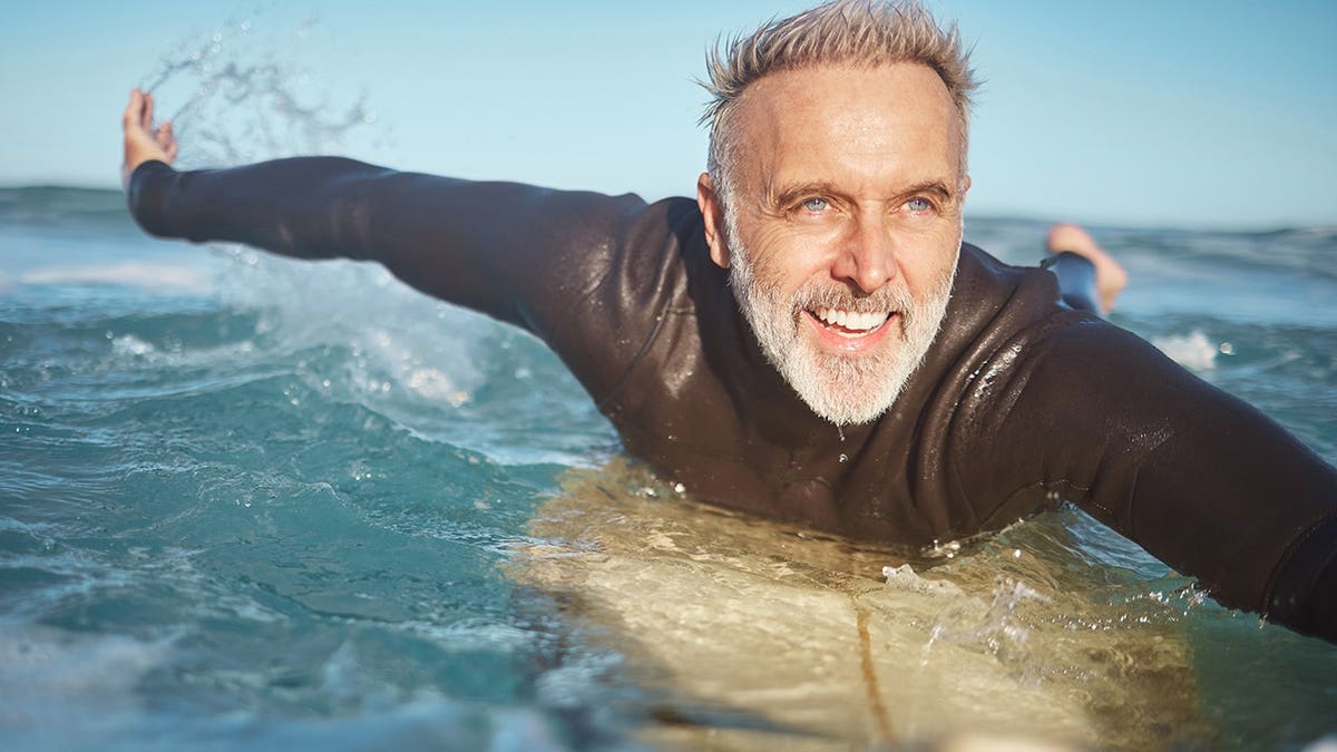 Senior man surfing in the ocean on a beach in Bali.