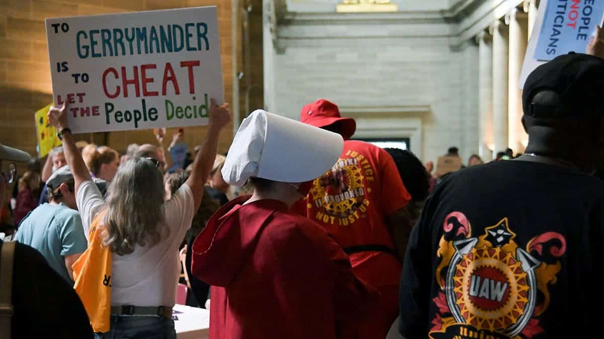 Woman in Handmaids Tale costume stands in Missouri Capitol rotunda during protest.