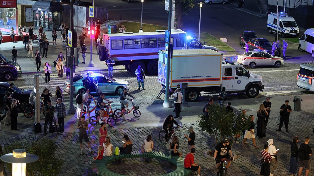 Law enforcement officers and emergency services personnel stand near an explosion site at a restaurant in central Moscow.