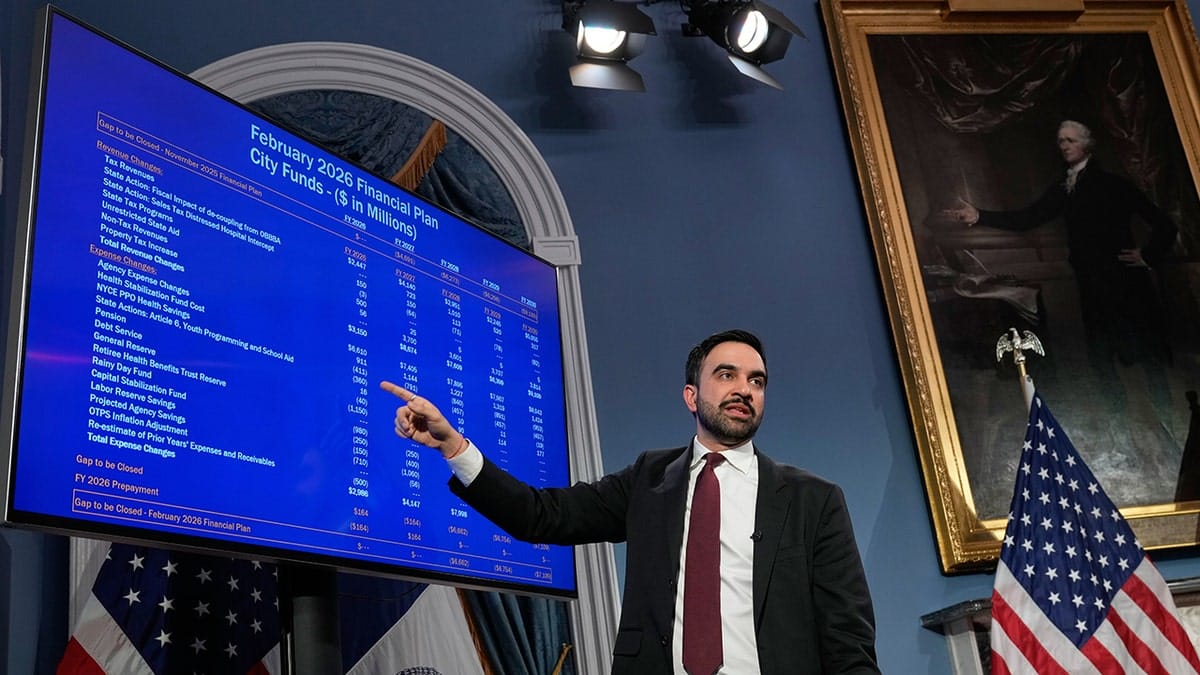 Zohran Mamdani speaking on New York City funding in front of a painting of Alexander Hamilton.