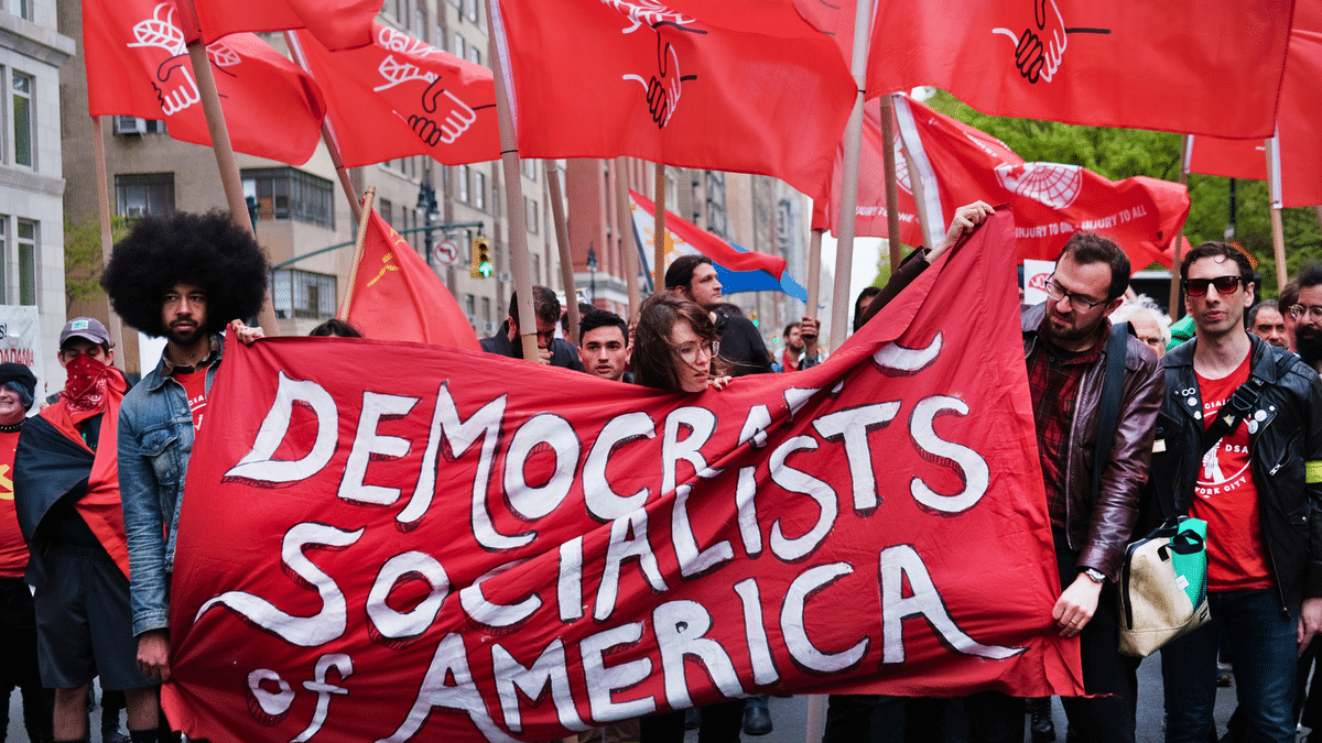 Members of the Democratic Socialists of America gather outside of a Trump owned building on May Day on May