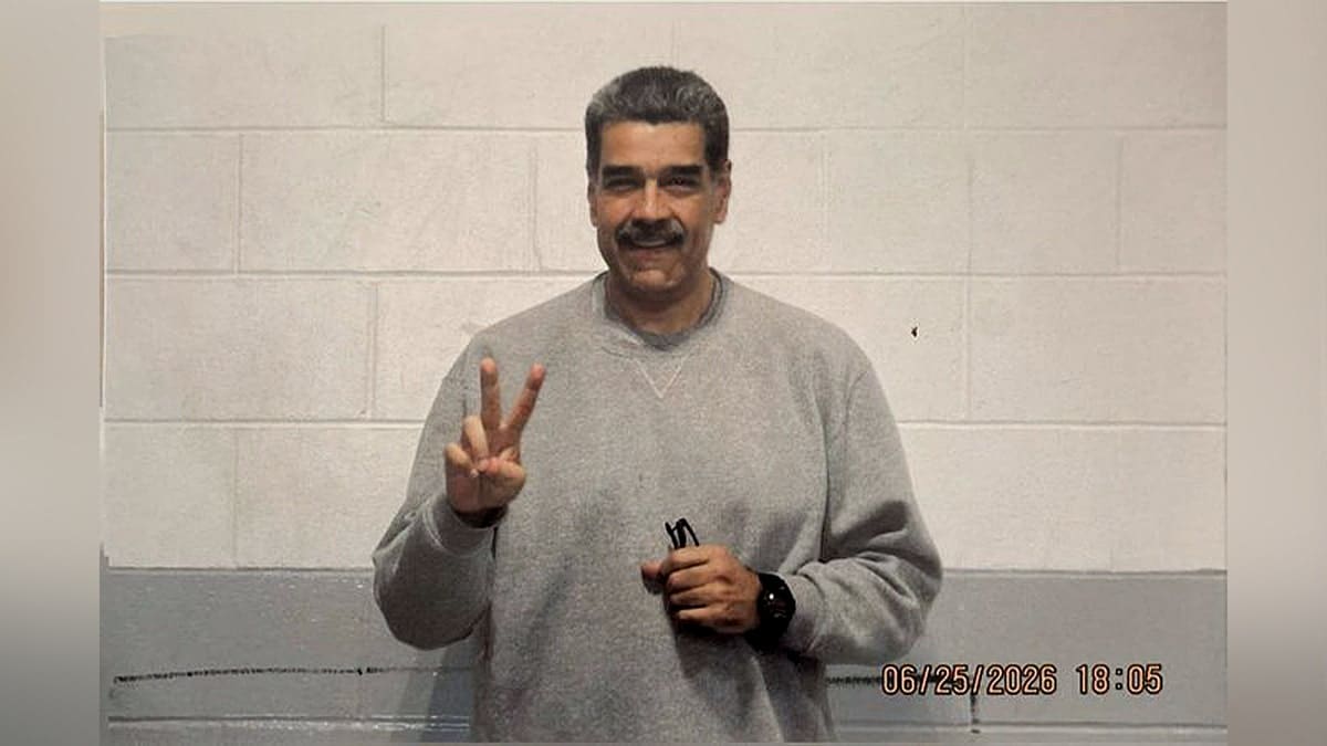 nicolas maduro in gray sweatsuit holding a peace sign and smiling