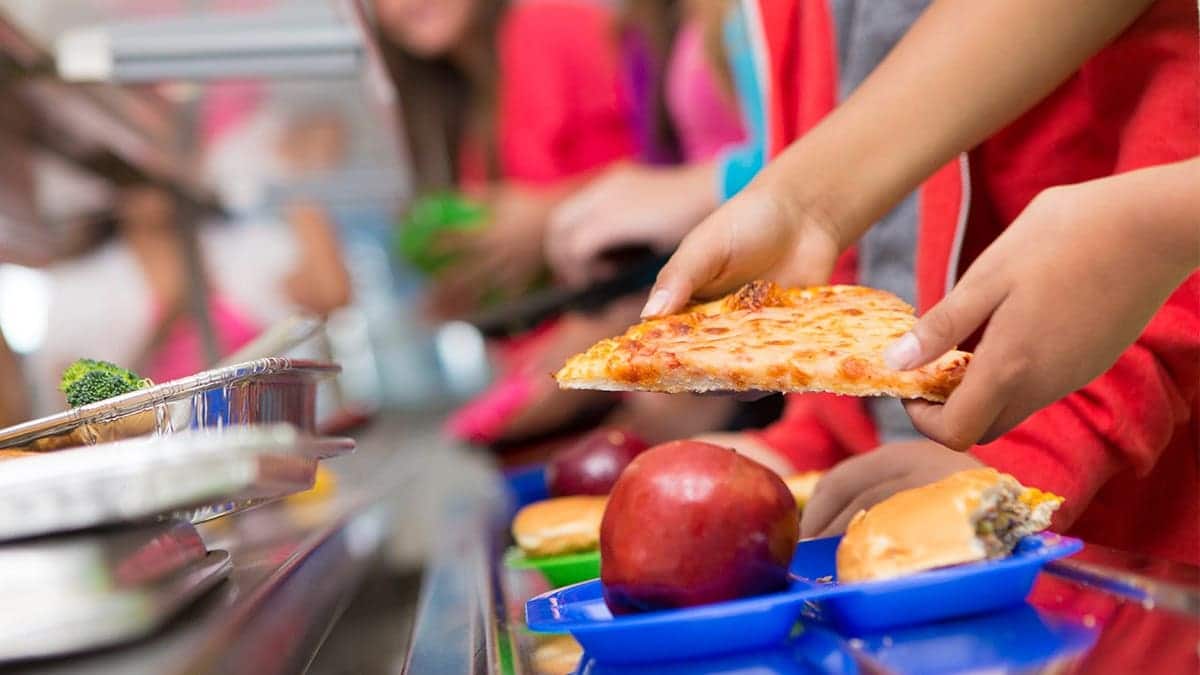 A student gets a piece of pizza and an apple