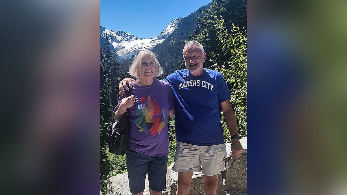 Elderly couple posing together outdoors in front of scenic mountains