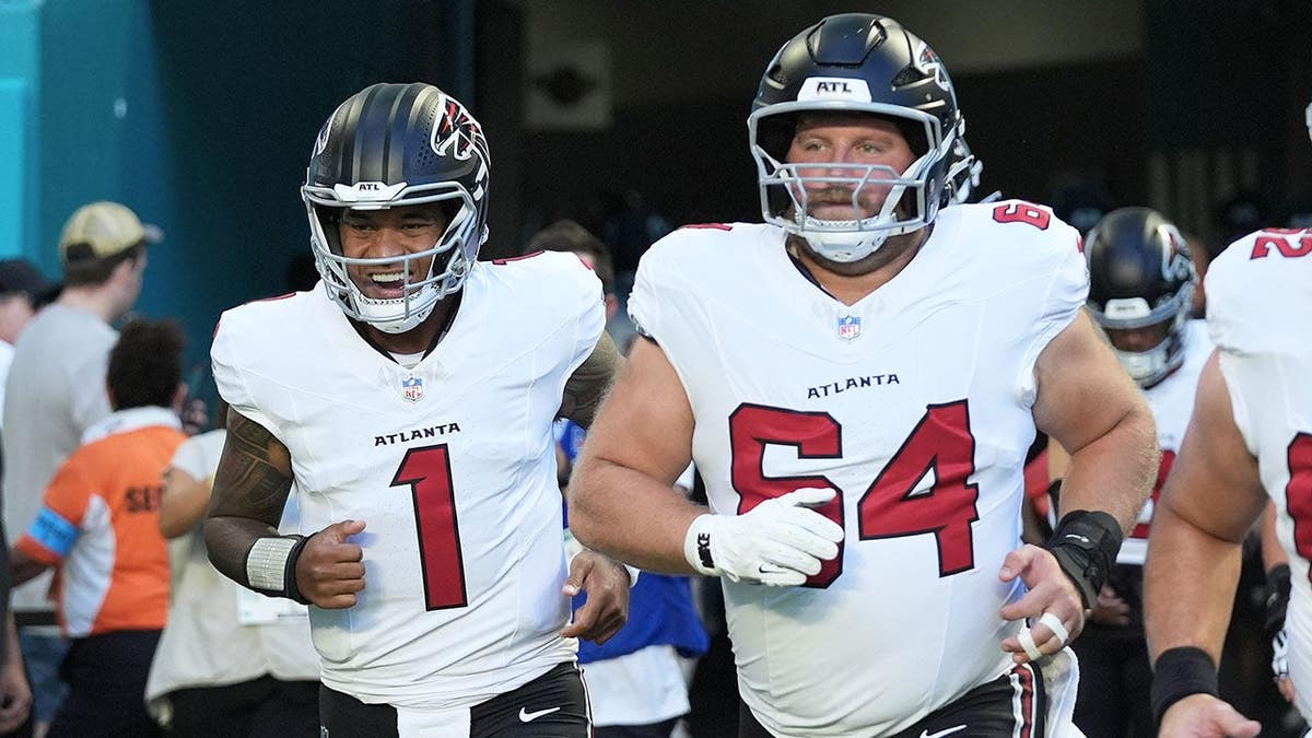 Tua Tagovailoa and Ryan Neuzil jog onto the field before an NFL preseason game.