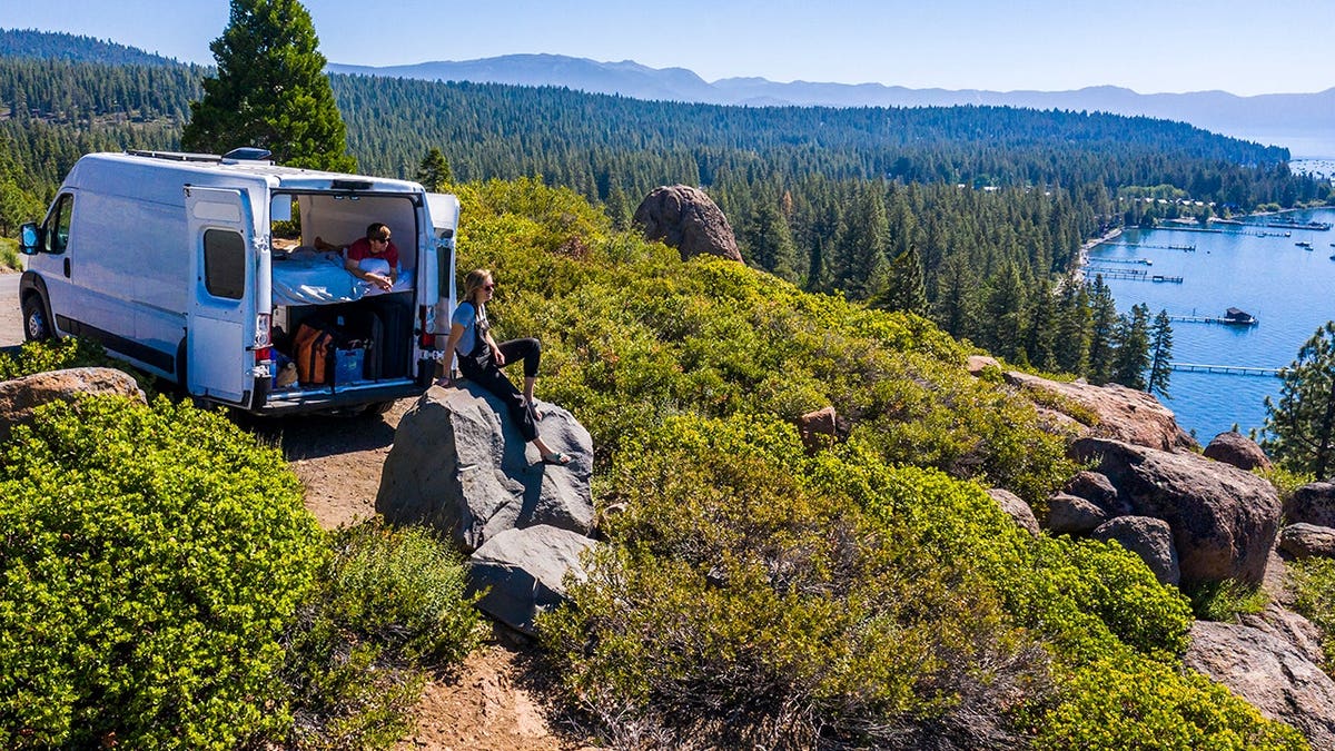 Young couple standing by a parked van at a Lake Tahoe viewpoint.