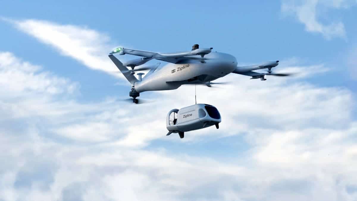 A drone carries a smaller delivery pod in the sky.
