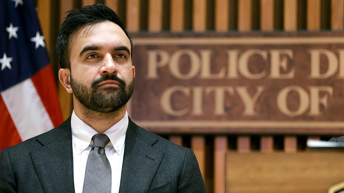 New York City Mayor Zohran Mamdani stands and listens during a news conference inside a police headquarters.