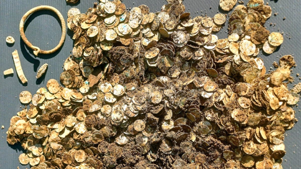 View of dirt-covered hoard, bracelet, various coins