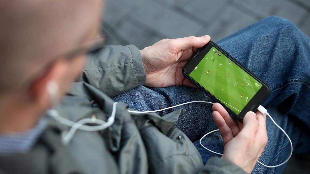 Man streaming a soccer game on his smartphone.