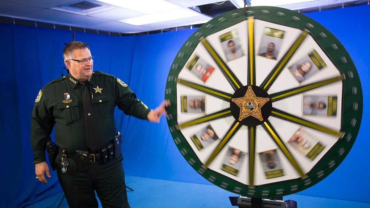 Brevard County Sheriff Wayne Ivey spins the Wheel of Fugitive board in a media studio.