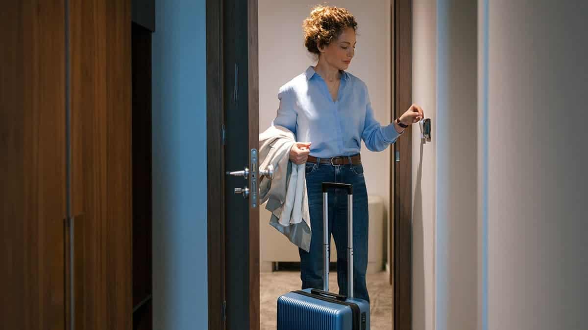 Woman uses a key to open a hotel room door and enters.