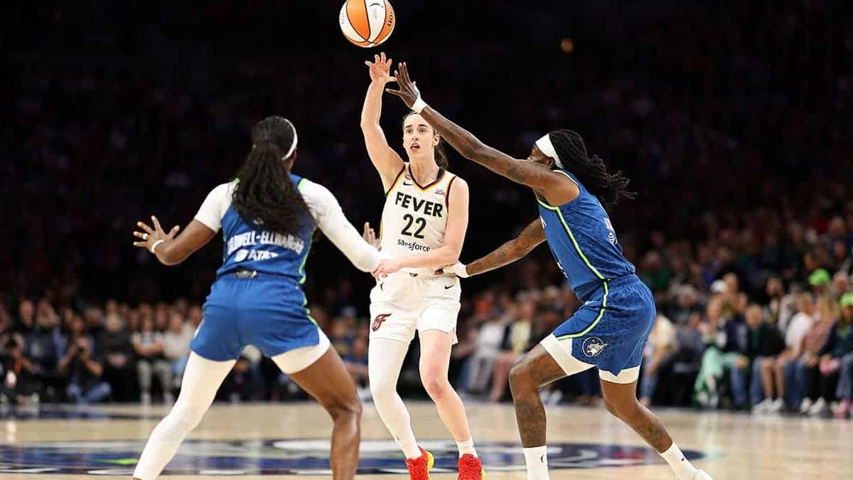 Caitlin Clark passes the ball against Maya Caldwell and Natasha Howard at Target Center.