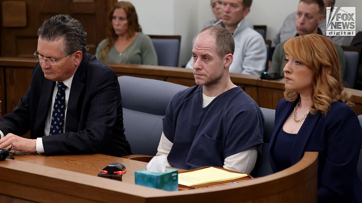 Caleb Flynn sitting at a table in a courtroom during a legal proceeding.