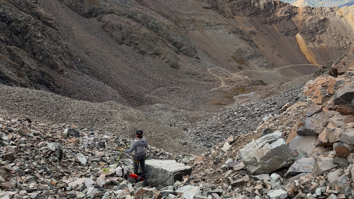 rescue personnel stands in rocky mountain landscape