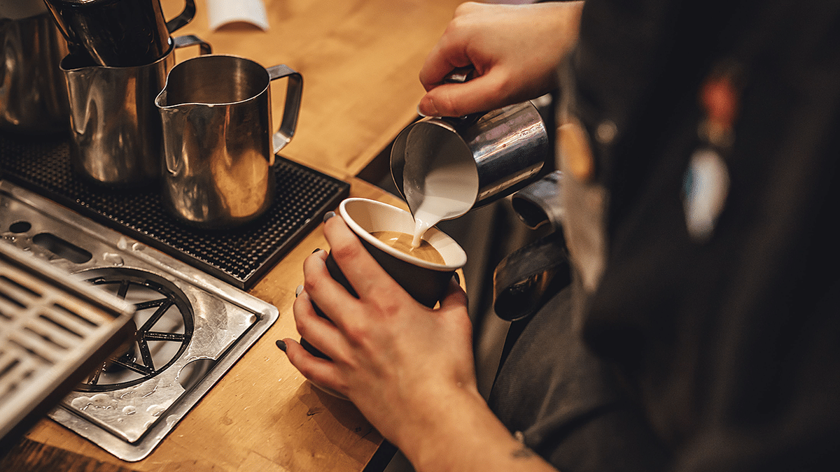 stock image of barista pouring milk into latte