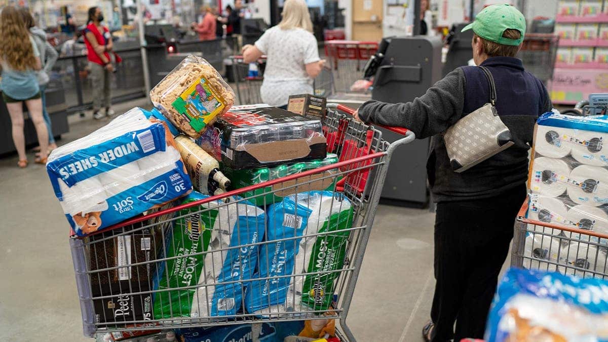 A woman with a full shopping cart shops at Costoc.