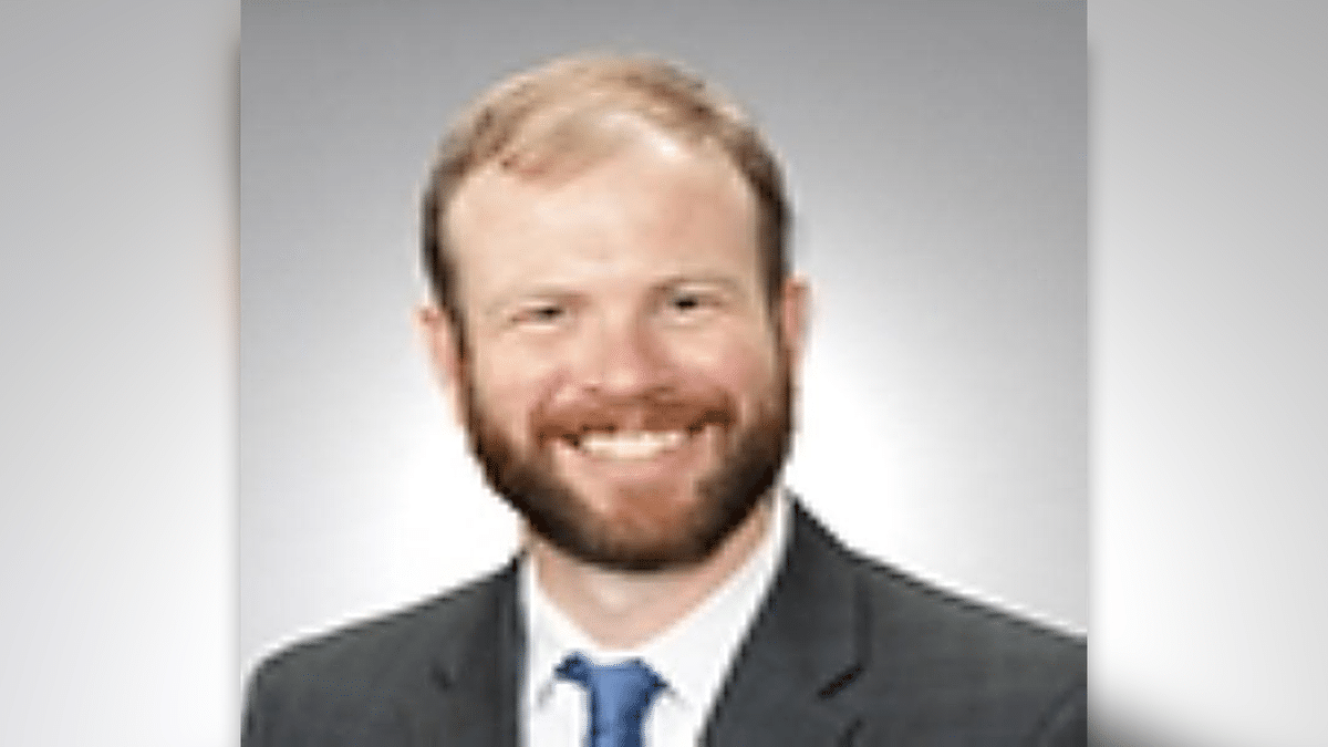A blurry photo showing Dr. Evans in a suit and tie, he has thinning, light colored hair and a full beard