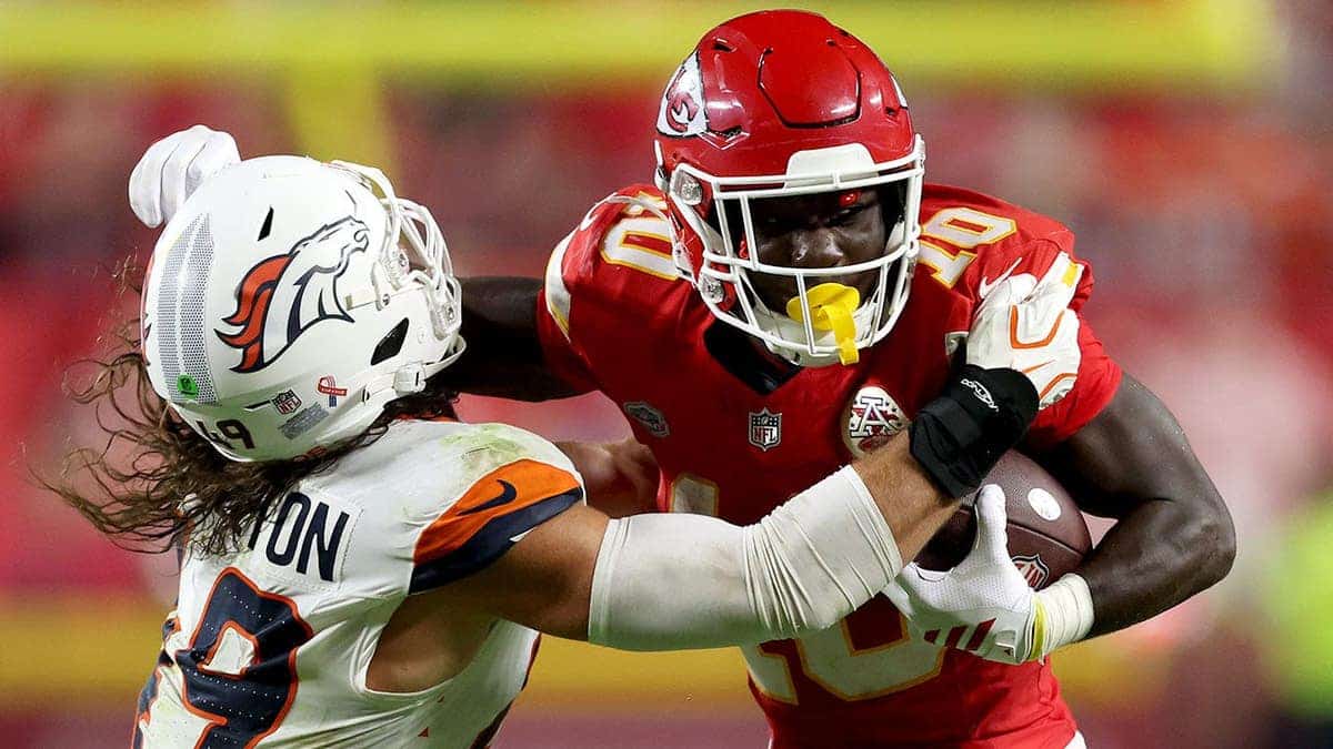 Emmett Johnson #10 runs with the ball against Alex Singleton #49 during an NFL game at Arrowhead Stadium.