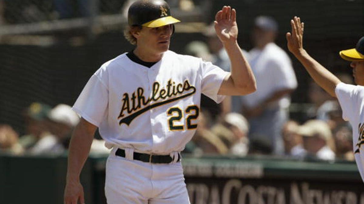 Eric Byrnes is congratulated after scoring a run during an Oakland Athletics game.