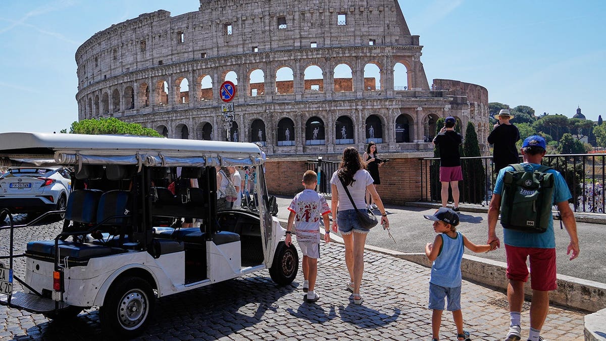 Golf cart parked near the Colosseum with tourists crowding surrounding streets in Rome.