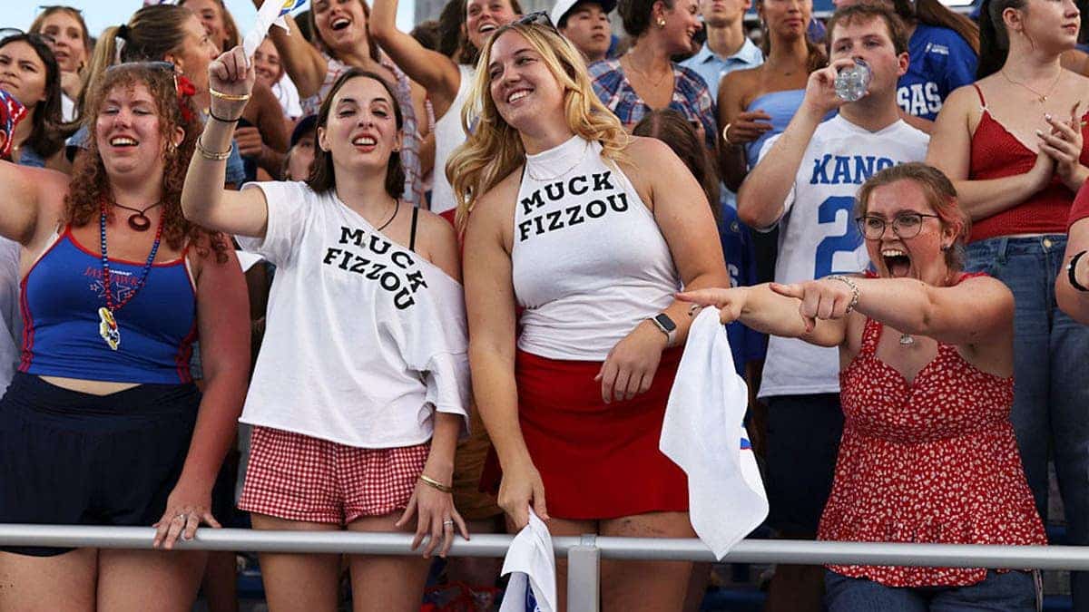 Kansas Jayhawks students wear shirts that say Muck Fizzou before a college football game.
