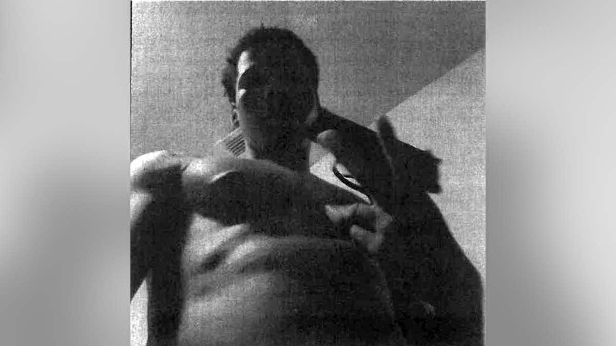 Grainy black-and-white image of Karmelo Anthony holding what appears to be a firearm close to the camera.
