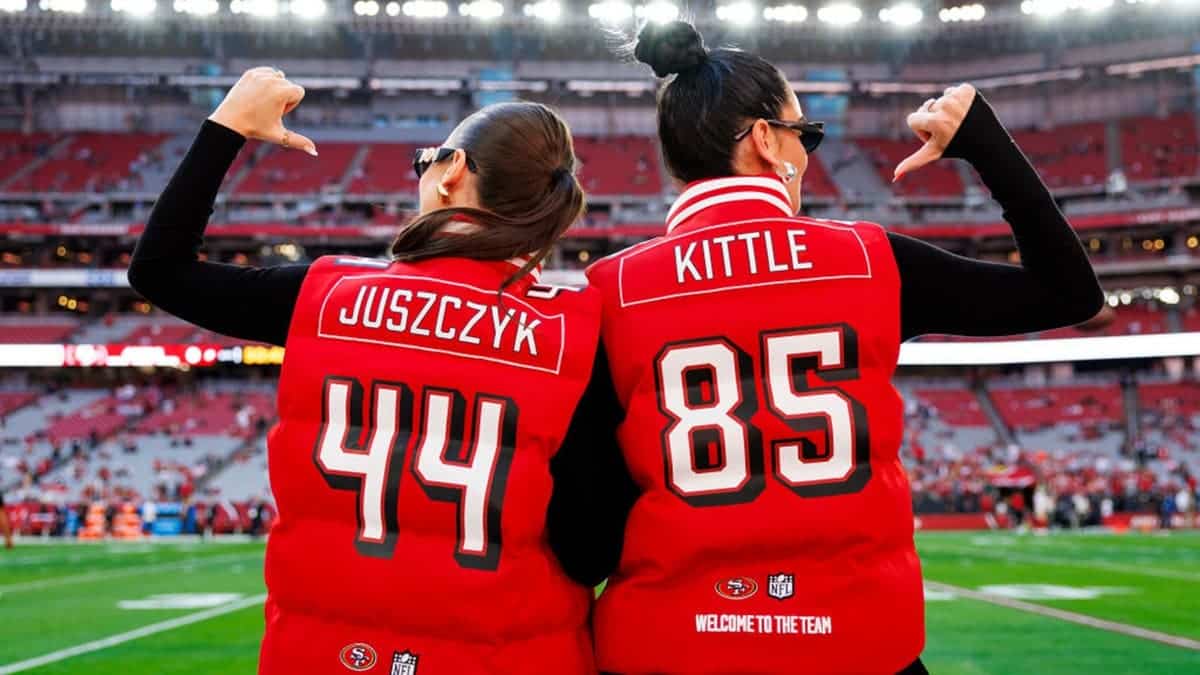 Kristin Juszczyk and Claire Kittle pose wearing Offseason vests at State Farm Stadium.