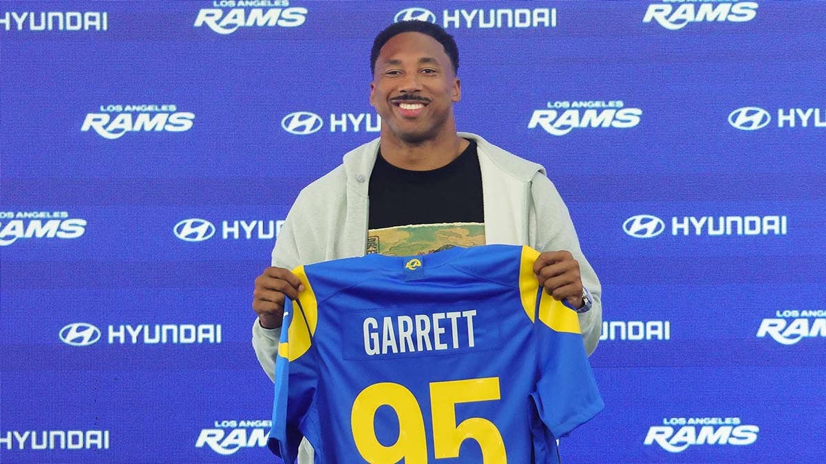 Myles Garrett of the Los Angeles Rams posing with his jersey at a press conference.