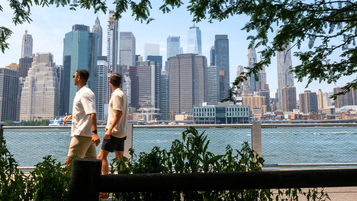 People walk by the NYC skyline.
