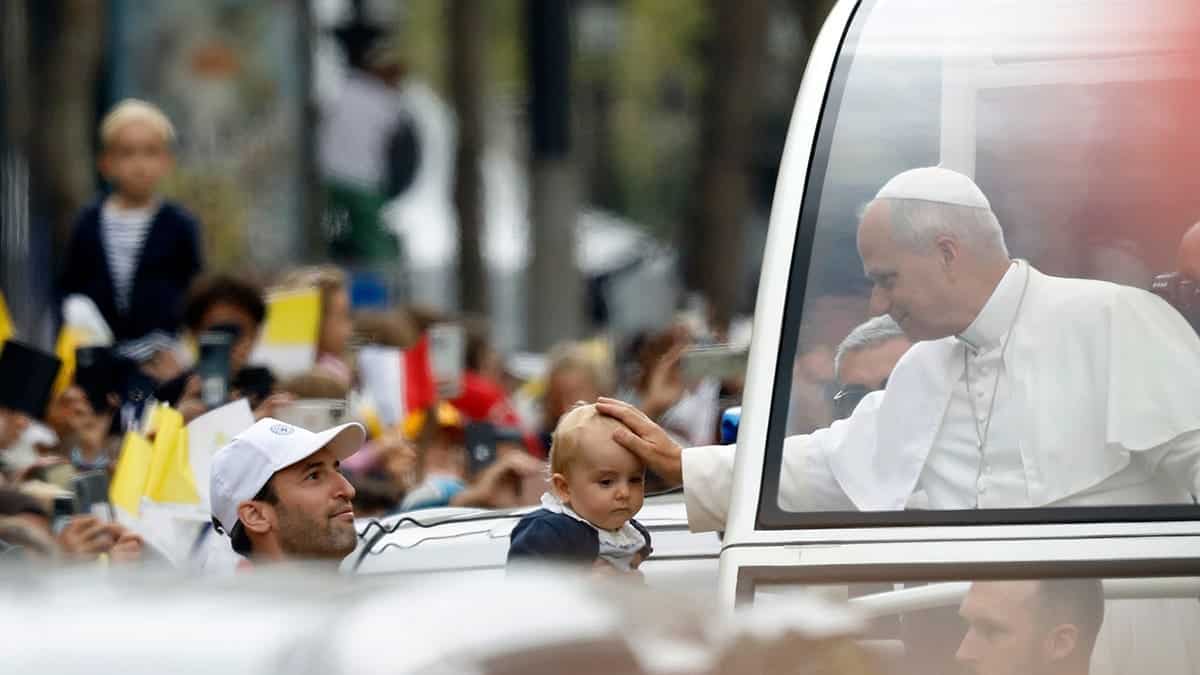 Pope Leo XIV waves from the popemobile on the Champs-Élysées in Paris.