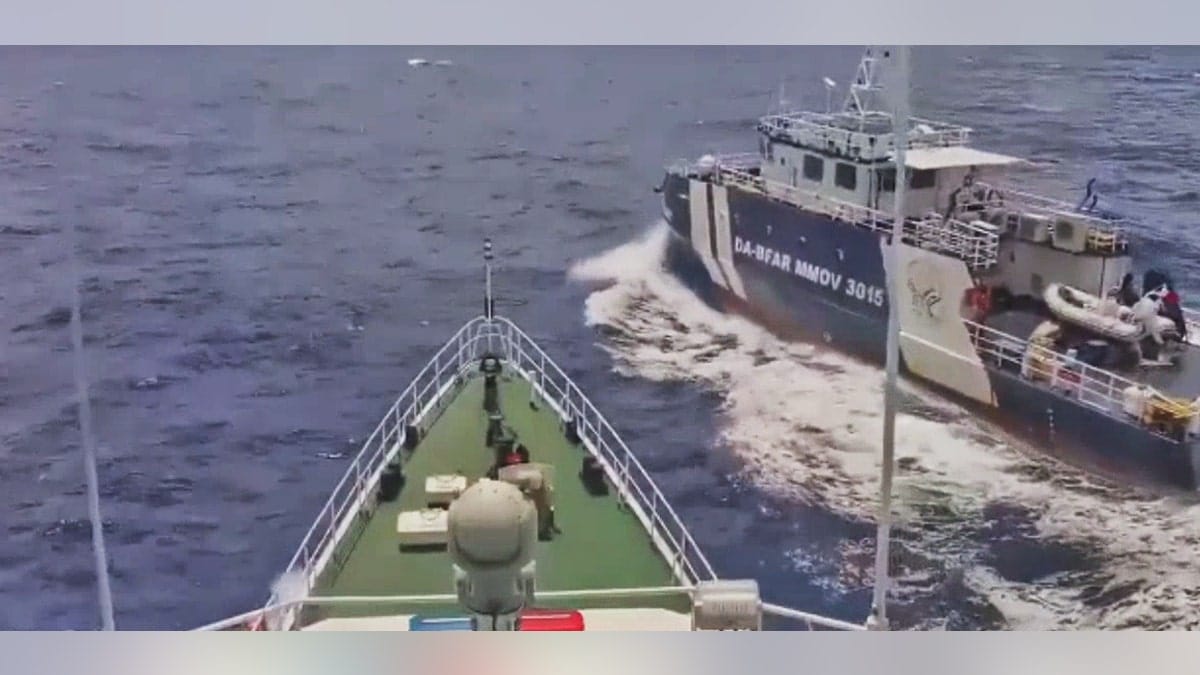 View from the bow of a ship directly approaching a Philippine Bureau of Fisheries and Aquatic Resources vessel, marked DA-BFAR MMOV 3015, as it crosses close by in open water