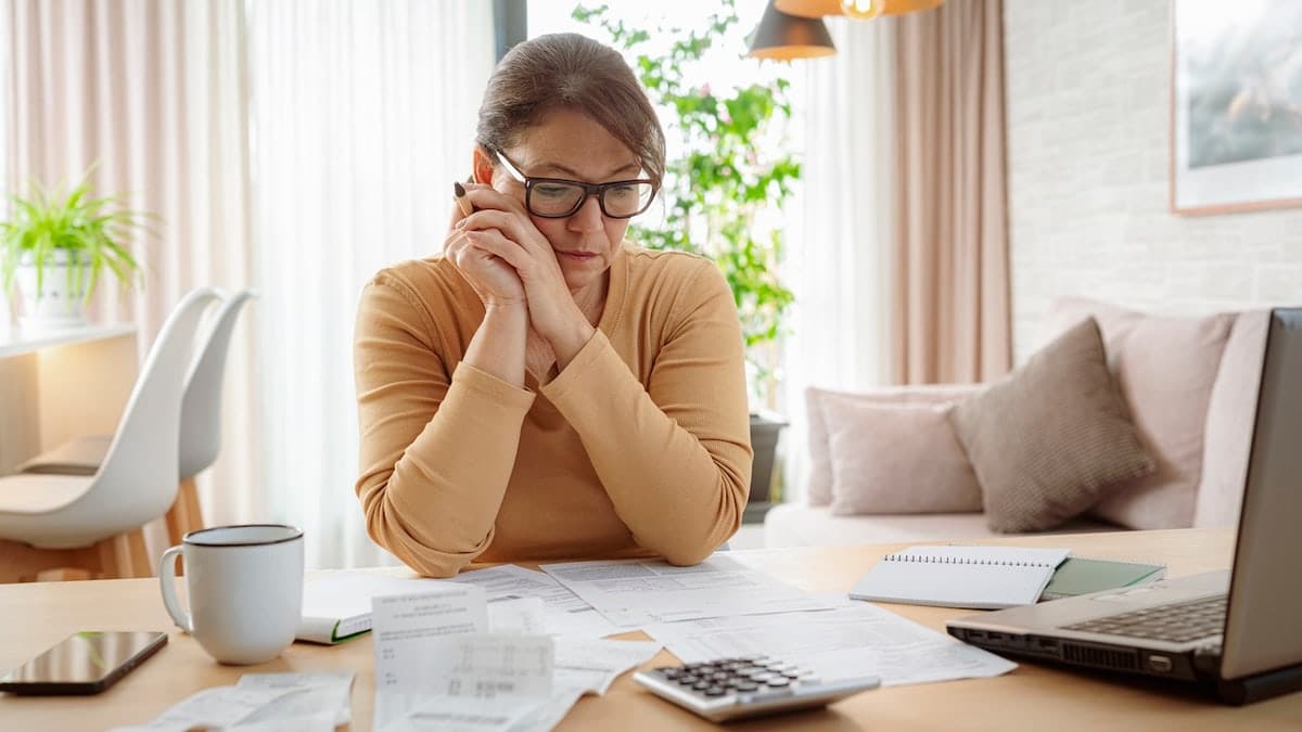 Mature woman contempling bills and tax papers at home