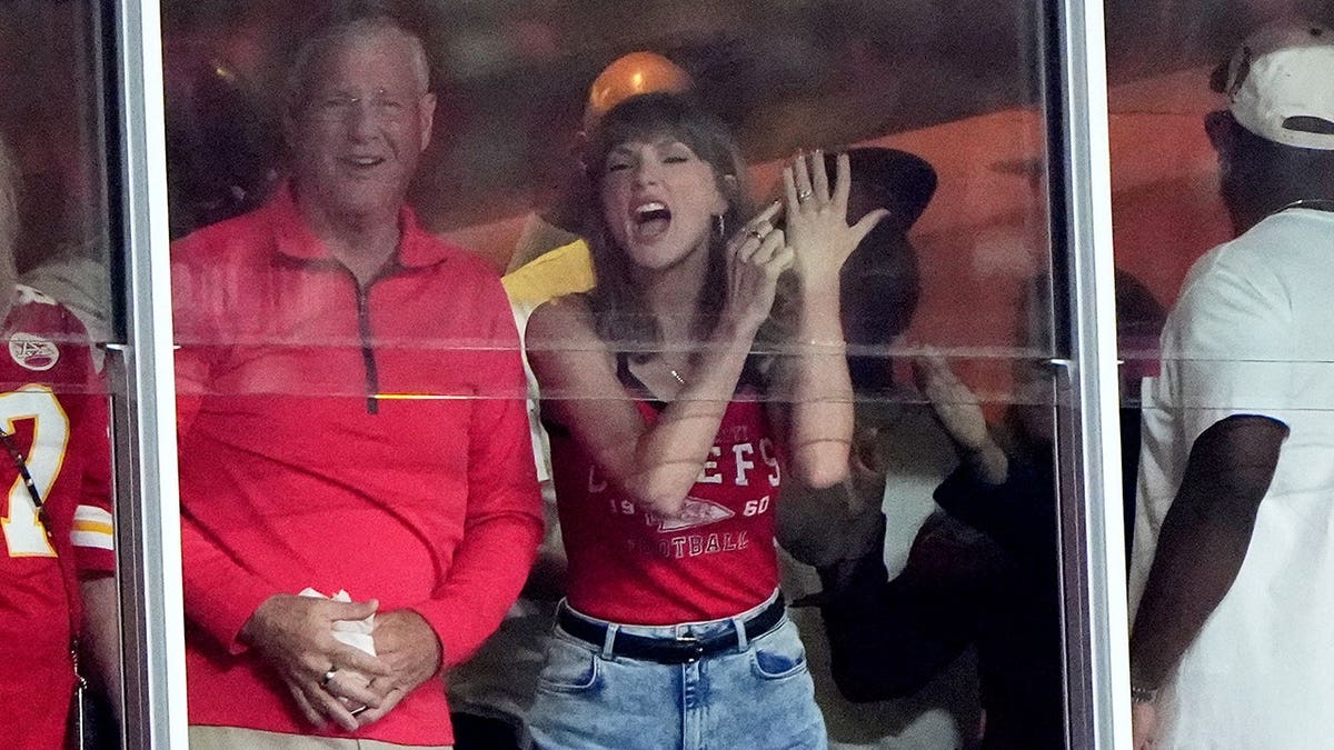 Taylor Swift celebrates with her father, Scott Swift, during an NFL game in Kansas City.