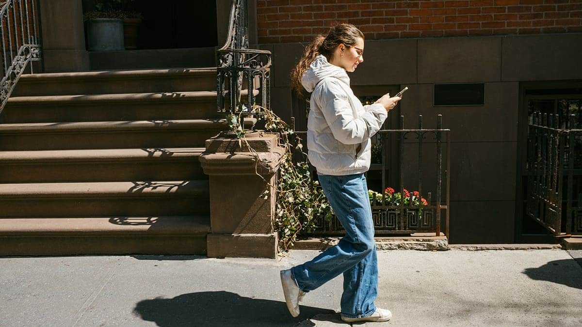 Teenage girl using smartphone while walking in New York City